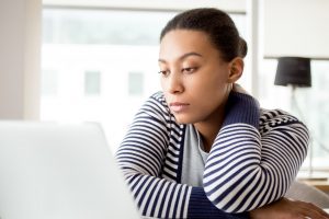 Woman reads laptop looking seriously