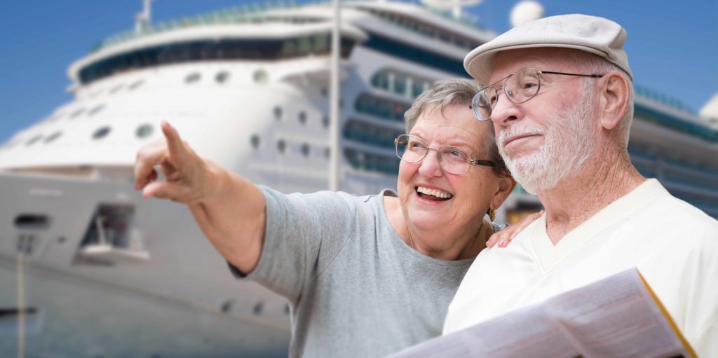 Traveling with cancer. Retired couple in front of cruise ship holding map