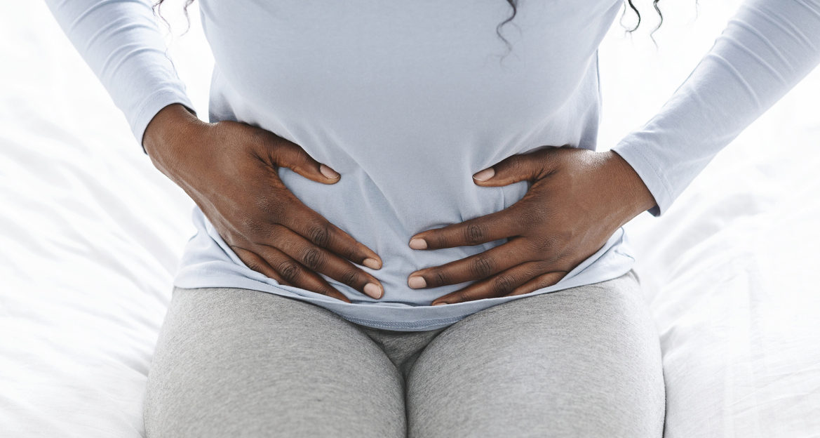 Woman holds stomach due to carciniod syndrome cramps