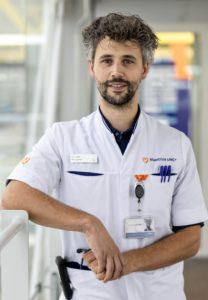 Jules Derks in white lab coat standing by a window.