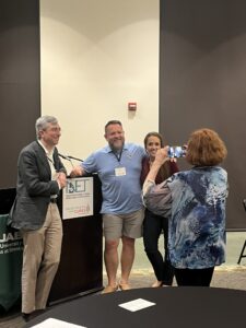 Two men and one woman pose as another woman takes a photo