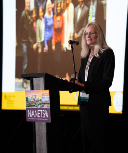 Woman at podium presenting in front of screen.