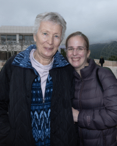 Two women outside in jackets smiling at camera. The one on the left is older.